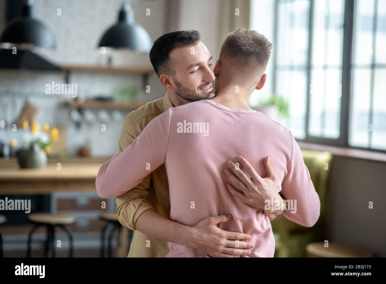 two-young-men-standing-and-hugging-each-other-2B3J173.jpg