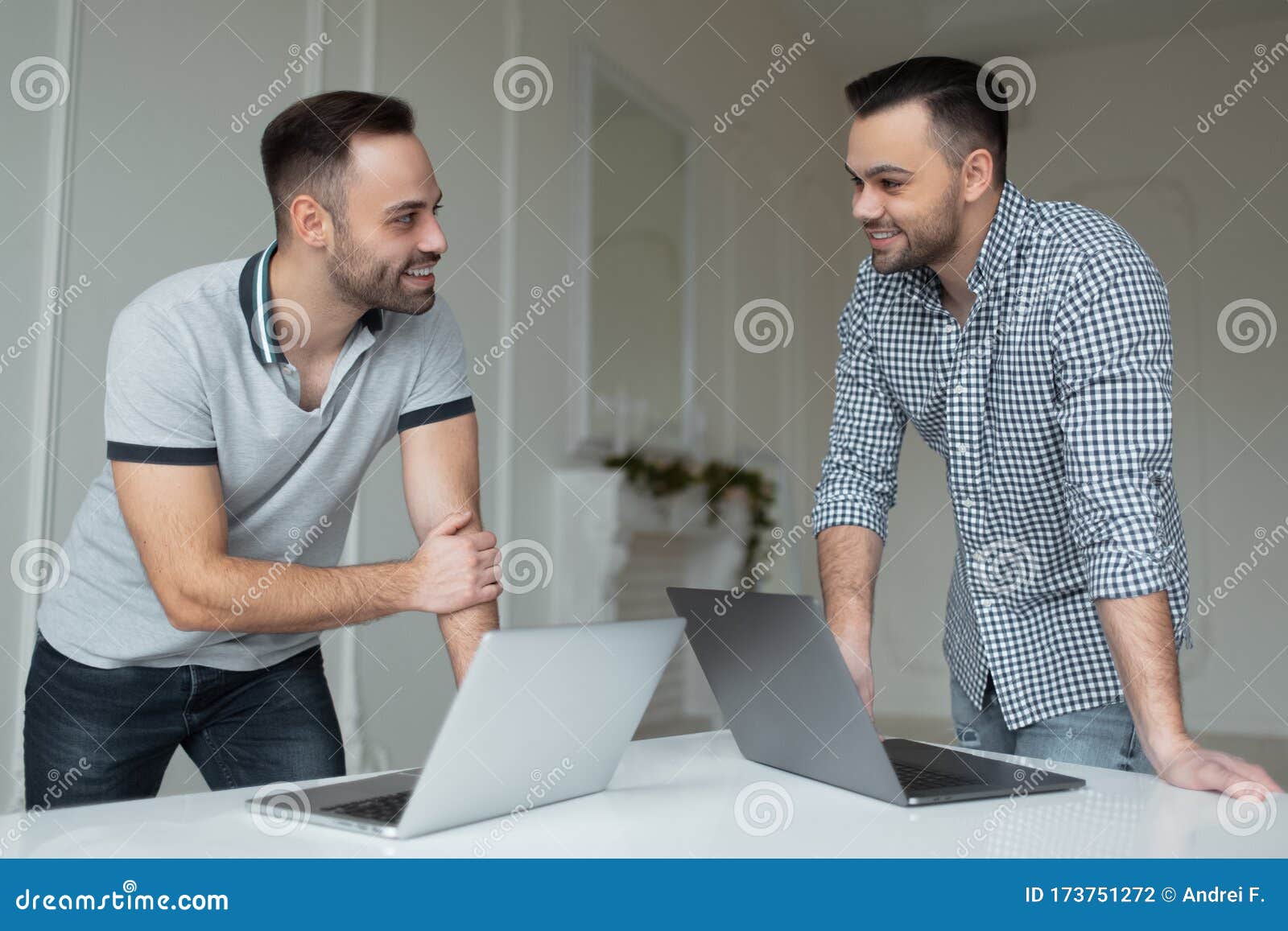 portrait-two-self-confident-businessman-working-laptop-one-men-talking-smartphone-another-guy-pointing-finger-173751272.jpg